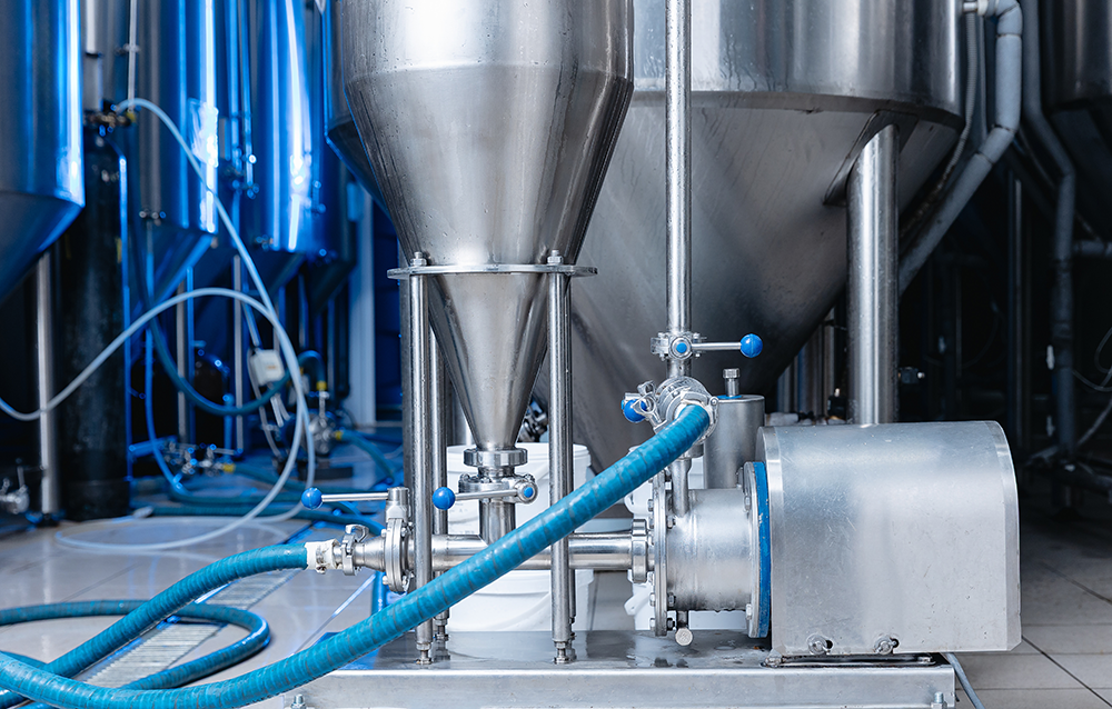 Industriell livsmedelsslang i bryggeriets jästankar, process för att blanda öl och juicer för att producera hantverksdrycken IPA.